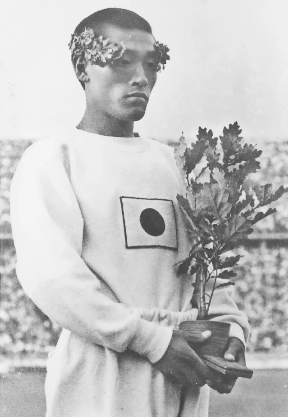 마라톤 시상식의 손기정 — 월계관을 쓰고 부상으로 받은 참나무 묘목을 들었다, 1936년 8월 9일
