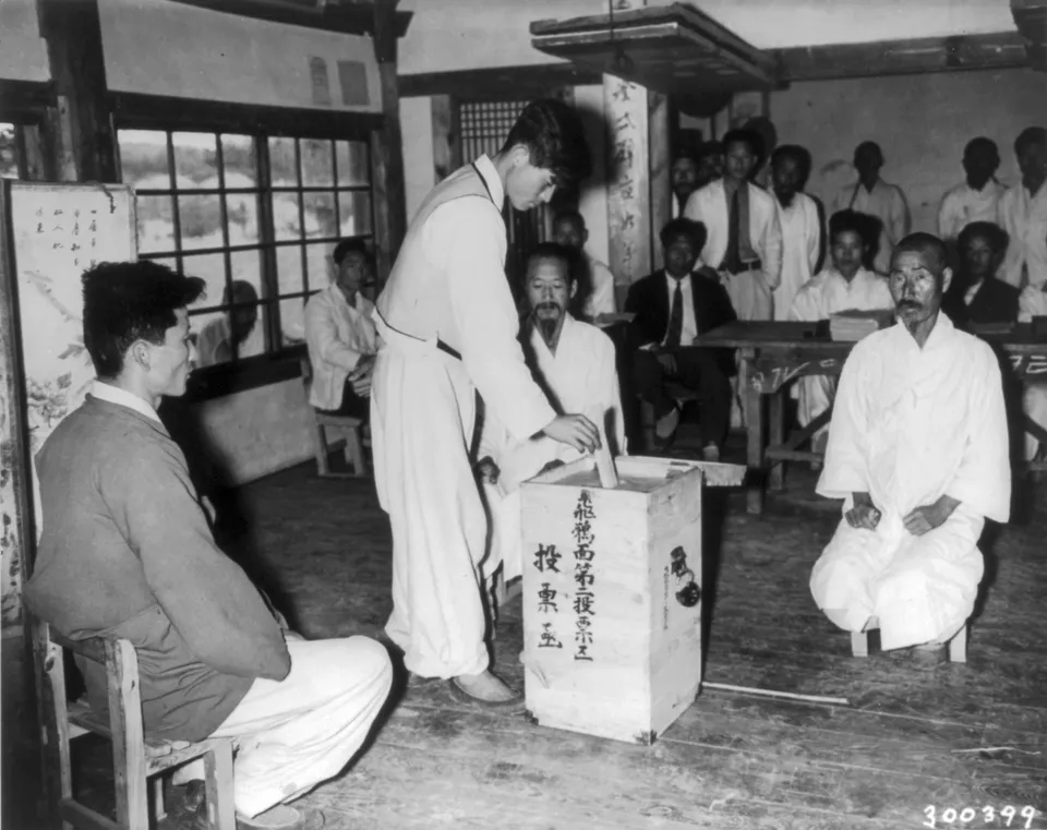 A voter casting his ballot before election officials in the 10 May 1948 general election