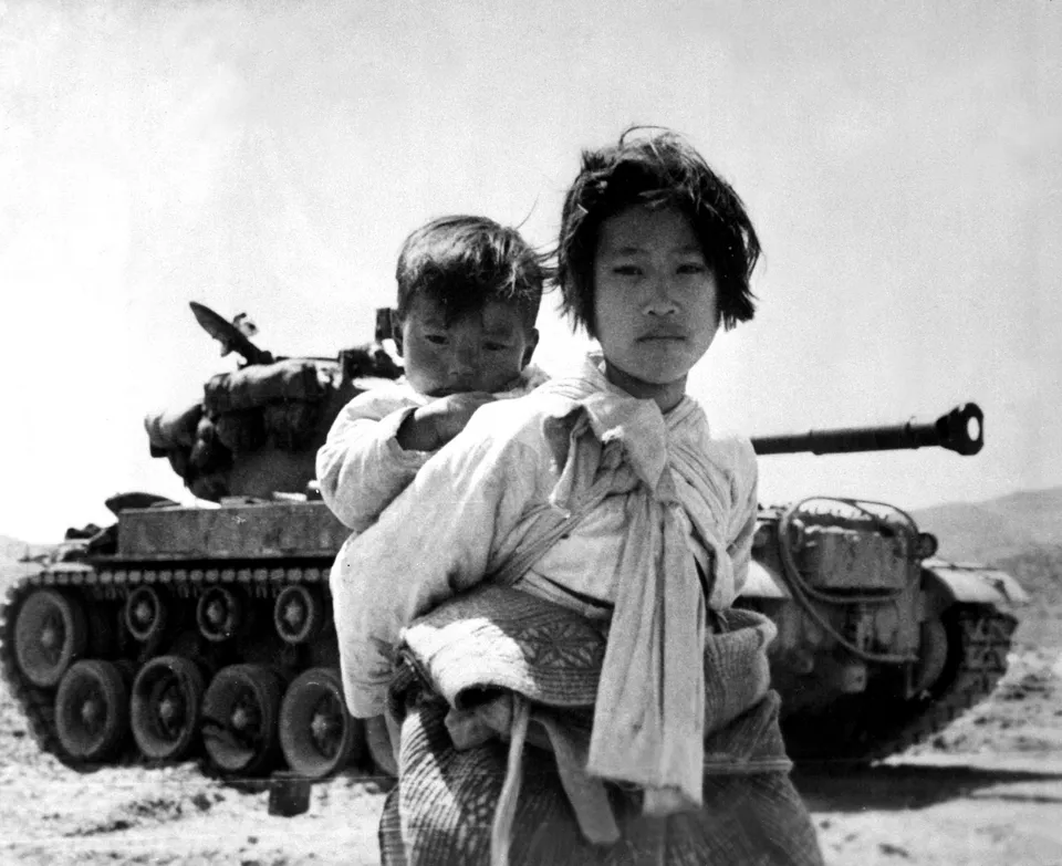 동생을 업고 멈춰 선 전차 곁을 지나는 소녀 — 행주, 1951년 6월 9일